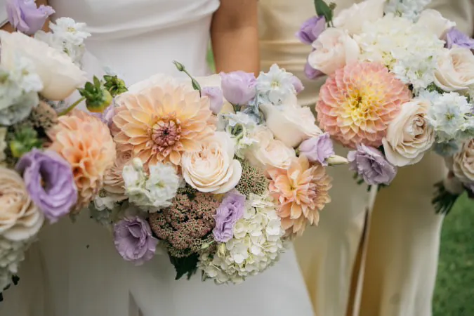Close view of wedding bouquets with peach, cream, pink and lilac flowers.