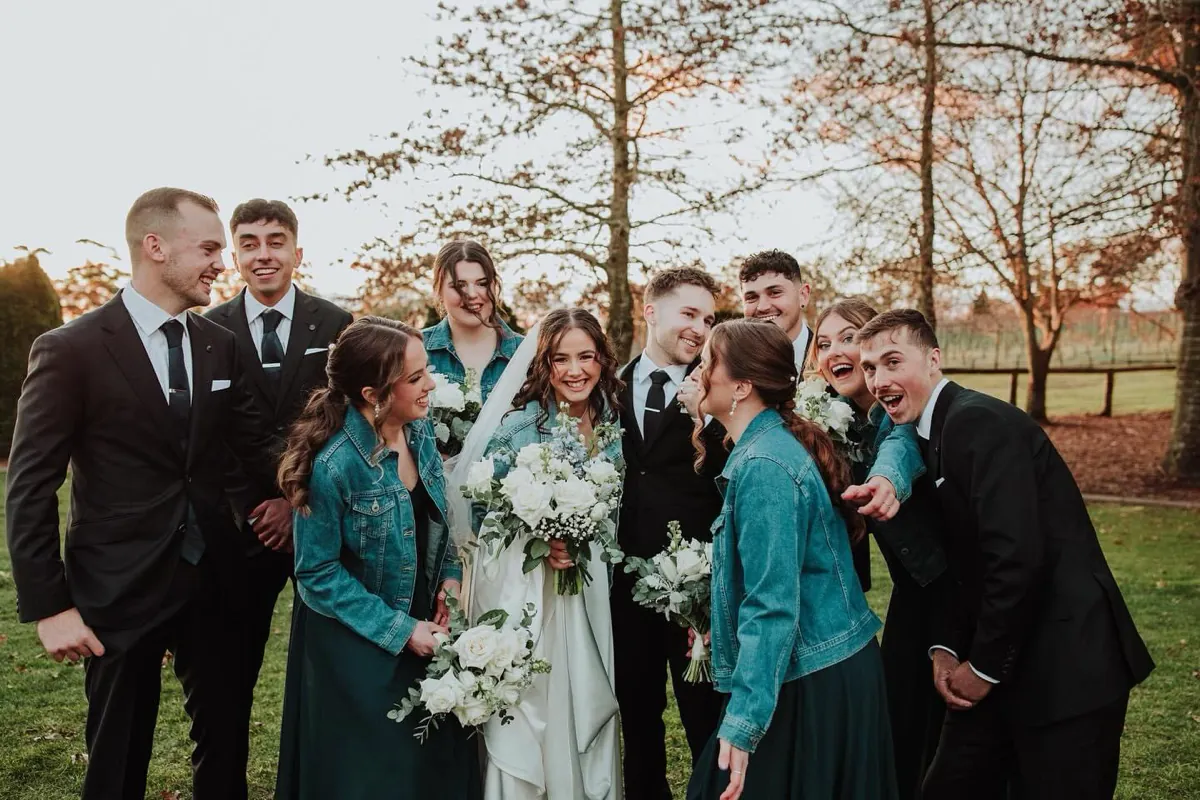Katelyn and Noah with their wedding party holding beautiful wedding bouquets by The Red Poppy Florist.