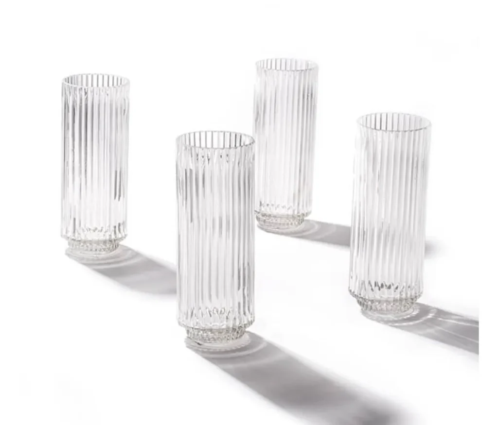 Four clear glass bud vases with vertical ribbing displayed on a white background.