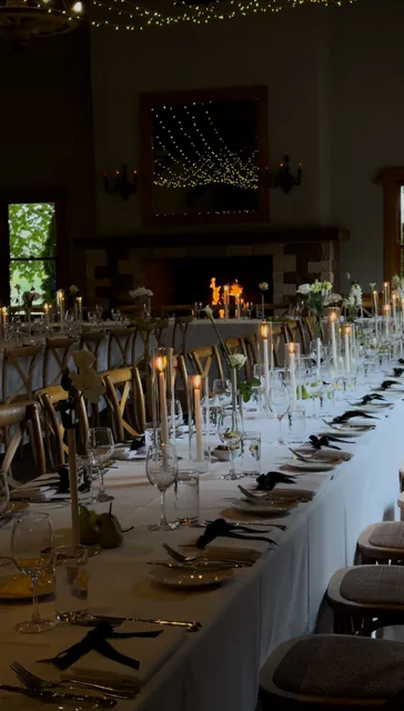Long wedding reception table set with glassware, candles and floral arrangements.